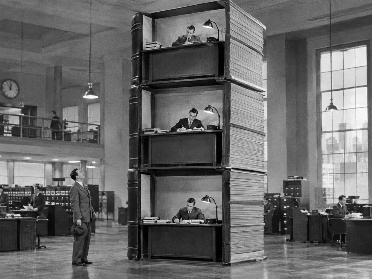 Трёхэтажная башня из книг учёта, на каждом этаже конторщик
